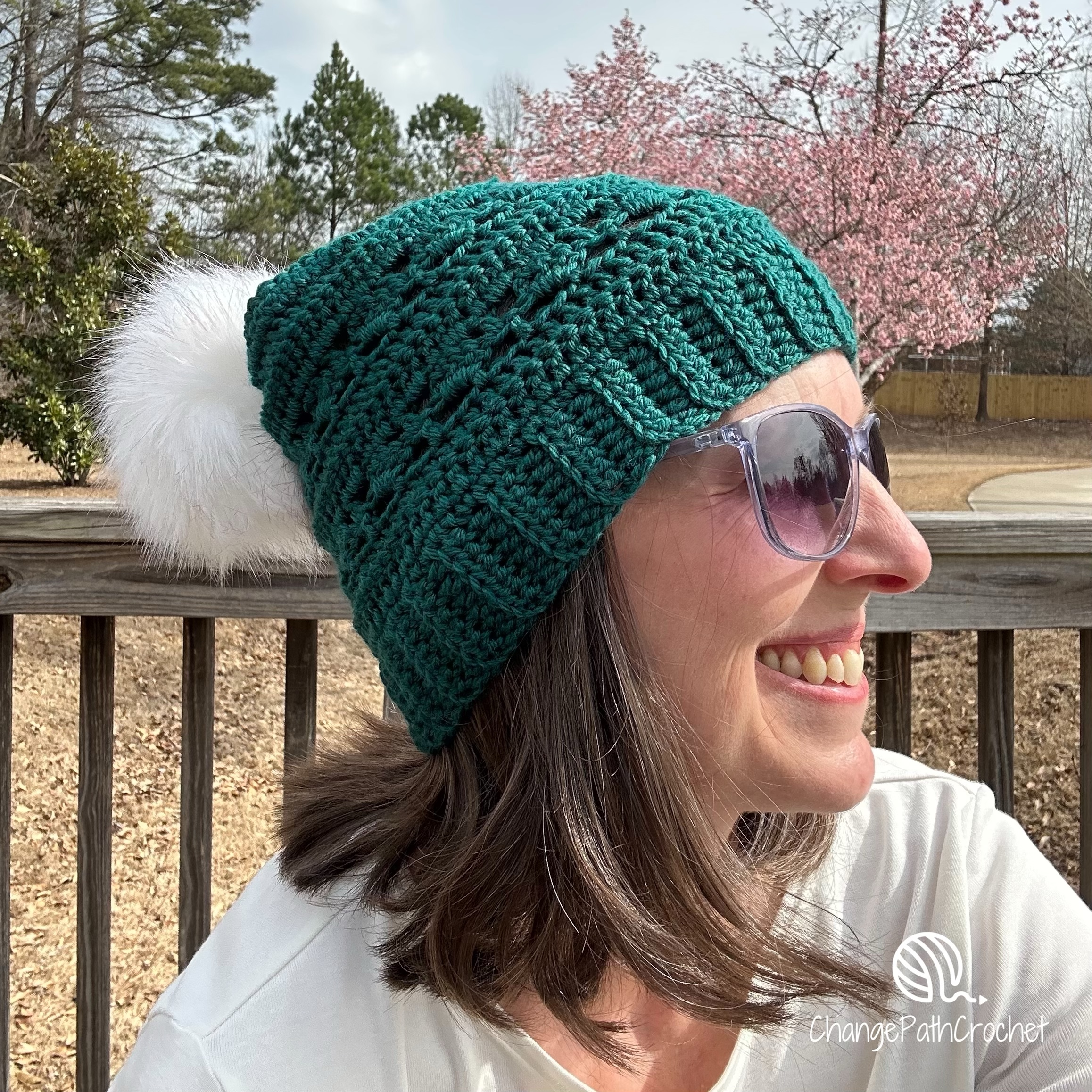 woman in sunglasses wearing a green beanie with a white pompom